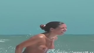 Sexy toned body walking naked on a crowded nudist beach