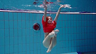 Slender and cute redhead white girl dives in the pool and undresses underwater