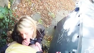 Adventurous blonde wearing earrings and black leather jacket kneels by the silver garbage bin sucking guy's cock in the public street