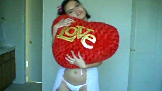 Black haired cutie hugs her big heart pillow on webcam