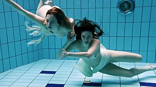 Two captivating young white girls under water in the pool