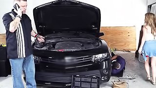 Beautiful blonde with tight skinny body wearing gold chain necklace kneels quietly by the black car and sucks black cock in the garage